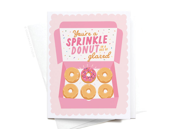 The Youre a Sprinkle Donut Greeting Card by Onderkast Studio features a pink donut box with five glazed donuts and one with pink frosting and sprinkles—an ideal premium card to celebrate someone who stands out.